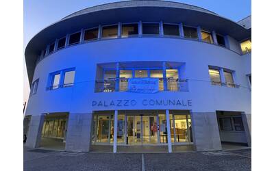 Palazzo comunal eilluminato di blu con striscione no alle bombe sui civili