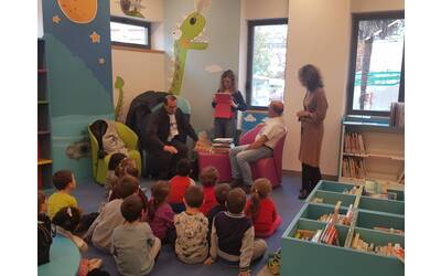 bambini seduti in biblioteca che ascoltano letture ad alta voce