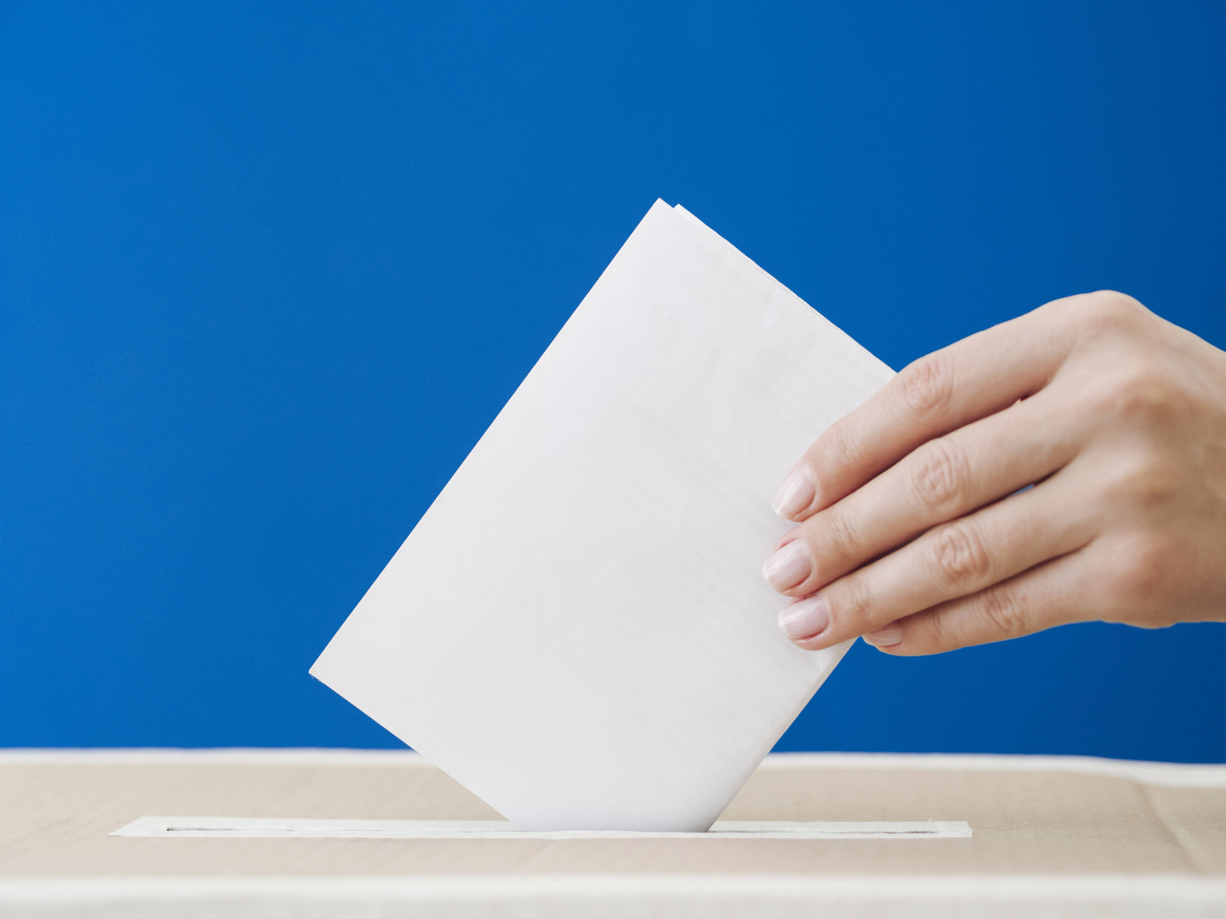 una mano che inserisce il suo voto nella cassetta