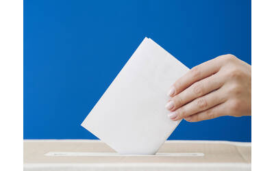 una mano che inserisce il suo voto nella cassetta